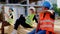 Group of construction workers and foreman middle-aged listening music at the lunch time they enjoying the time dancing