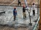 Group of construction workers pouring wet concrete using the concrete hose from the concrete pump into the timber formwork at the