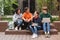 Group of cool smiling students sitting and happily looking at each other while spending time together in courtyard of