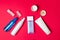 Group of cosmetic bottles on red colored paper background