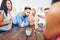 Group of creative friends sitting at wooden table. People having fun while playing board game