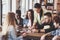 Group of creative friends sitting at wooden table. People having fun while playing board game