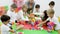 Group of cute children playing with colorful blocks with help of teacher