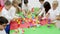 Group of cute children playing with colorful blocks with help of teacher