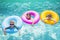 Group of cute kids playing on inflatable tubes in a swimming pool on a sunny day