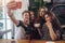 Group of cute teenagers taking selfie with cellphone while sitting in a restaurant with interior in retro style