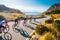 Group of cyclist ride together on road bicycles in beautiful nature. Sunset light, sea in background