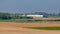 Group of cyclists pedaling on a road in a cycling competition between farm fields and an airport in the background