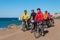 Group of cyclists riding sandy beach mountain bike with backpack.