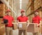 Group of delivery men holding cardboard boxes in a storage