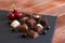 Group of different chocolates, milk and dark, on a black background with red cherries. Wooden table