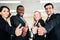 A group of diverse businesspeople showing raised thumbs at the camera. Recommendation of good choice. The diversity of African and