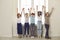 Group of diverse children of classmates stand with raised hands in the school corridor.