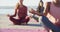 Group of diverse female friends meditating at the beach