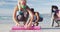 Group of diverse female friends wearing face masks rolling yoga mats at the beach