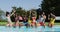 Group of diverse friends dancing and enjoying while sitting by the pool