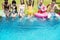 Group of diverse friends splashing water at the swimming pool