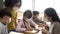 Group of diverse students in school building discussing in group study class. Elementary pupils are wearing a face mask