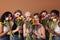 Group of diverse women hide their faces by bouquets of flowers. Portrait of six females of a different race, age, and figure type