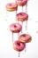 A group of donuts with pink icing and sprinkles. Digital image.