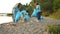 Group of eco activists girls and guys busy picking garbage on lake beach