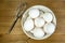 A group of eggs inside a deep white bowl next to a whisk waiting for the chef to use them in a meal