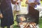 Group of elderly are rotating meat and vegetable on a stick that is being grilled