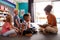 Group Of Elementary School Pupils Sitting On Floor Listening To Female Teacher Read Story