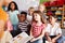 Group Of Elementary School Pupils Sitting On Floor Listening To Female Teacher Read Story