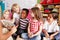 Group Of Elementary School Pupils Sitting On Floor Listening To Female Teacher Read Story