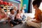 Group Of Elementary School Pupils Sitting On Floor Listening To Female Teacher Read Story