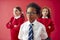 Group Of Elementary School Pupils Wearing Uniform Folding Arms Against Red Studio Background