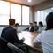 A group of employees are sitting in a meeting room through a blurred lens