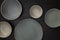 Group of empty blank ceramic round bowls and plates on black stone blackground, Top view of traditional handcrafted kitchenware