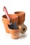 Group of empty, stacked, used terracotta planting pots with gardening tools and shovel over white