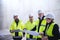 A group of engineers standing on construction site, holding blueprints.