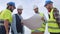 Group of engineers and workers looking at a blueprint s in a windmill park.