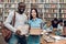 Group of ethnic multicultural students in library. Black guy and asial girl with books.