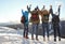 Group of excited friends with backpacks enjoying mountain view