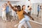 Group of excited young adult people dancing dynamic moves in pairs during lesson in dance class