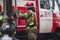 Group of fire men in uniform during fire fighting operation in the city streets, firefighters with the fire engine truck fighting