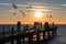 A group of fishermen standing on a pier at sunset