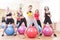 Group of Five Caucasian Female Athletes Having Exercises With Fitballs in Gym and Showing Thumbs Up