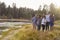 Group of five happy friends walking near a rural lake