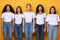 Group Of Five Serious Multiracial Ladies Standing Over Yellow Background