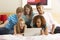 Group Of Five Teenage Using Laptop In Bedroom