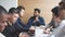 Group focused male business people gathered around computer in office talking.