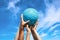Group of football fans holding blue soccer ball in blue cloudy sky. Kid s and adult s hands together hold ball