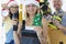 Group of foreman repairmen in santa claus hats holding drill and alarm clock near christmas tree closeup