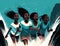 A group of four African girls confidently jumping in front of an aquamarine waterfall faces illuminated by the sparkling